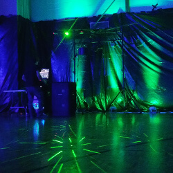 The DJ's at a formal eighth grade dance with green uplighting
