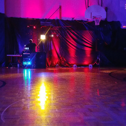 The DJ's at a formal eighth grade dance with red uplighting